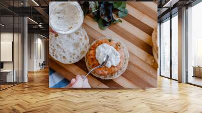 A woman hand putting homemade tartar sauce over a salmon and prawns hamburger. Vegetarian Food Wall mural