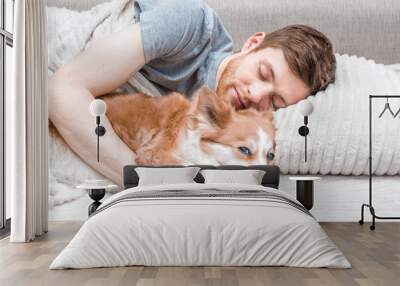 Young man sleeping in bed hugging a dog Wall mural