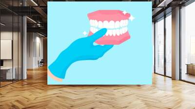 Vector cartoon hand of a dentist in a blue glove that hold a dental phantom or plastic model of human jaw. Wall mural