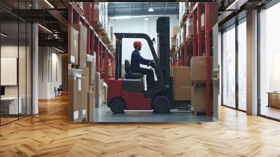 A worker in a logistics warehouse is organizing boxes with a forklift surrounded by shelves filled with goods Wall mural