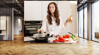 Brunette woman preparing fresh fish steak on the kitchen with vegetables and glass of white wine. Housewife concept Wall mural