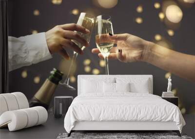 Close up of dark skinned man and caucasian woman toasting with glasses of sparkling wine on gray background with lights and lens flare Wall mural