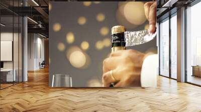 Close up slowmotion of man's hands opening a bottle of champagne on gray background with lights and flares Wall mural