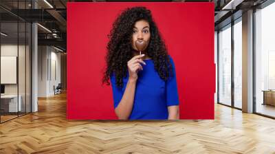 happy black woman with heart shaped chocolate candy smiling on red background Wall mural