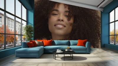 mixed race black woman portrait with big afro hair, curly hair in beige background smiling and laughing closeup Wall mural