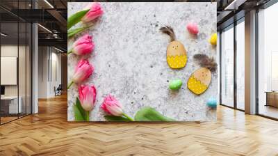 Easter composition with pink tulips, wooden chicken toys, colorful eggs and copy space against grey textured background. Top view, flat lay Wall mural