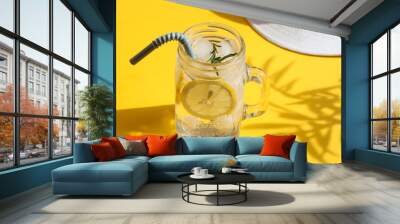 Summer composition. Cold lemonade with ice and lemon and a hat on a bright yellow background with deep palm tree shadows. Summer, vacation concept. Close-up Wall mural