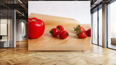 red cherry tomatoes, red bell pepper and strawberries on a parchment paper , white background Wall mural