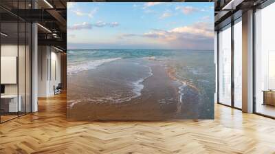 Seashore at sunset, sand is washed from two sides by waves, clouds in the sky, panorama Wall mural