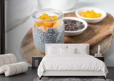 Chia pudding in glass jar with almond milk and mango on white background Wall mural