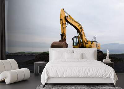 Yellow excavator on black sand against the backdrop of mountains. Construction in Iceland. Beautiful nature Wall mural