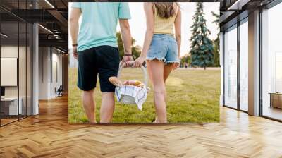 young romantic couple holding picnic basket with fruits in the park Wall mural