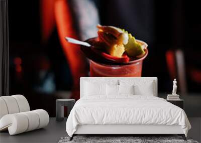 Young male bartender hands over a glass of Bloody Mary drink, garnished with pickled vegetables, close up vertical image  Wall mural