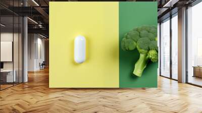 Concept of illness and health, prevention vs medication. Healthy food, not pills or drugs. Stalk of fresh nutritious broccoli and a medication capsule isolated on yellow background Wall mural