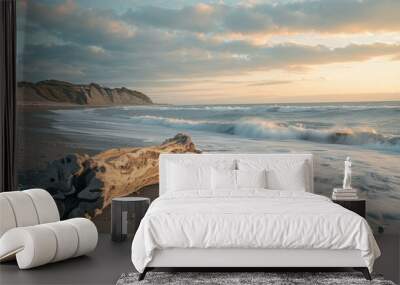 Driftwood on sandy beach with waves and dramatic sky at sunset Wall mural