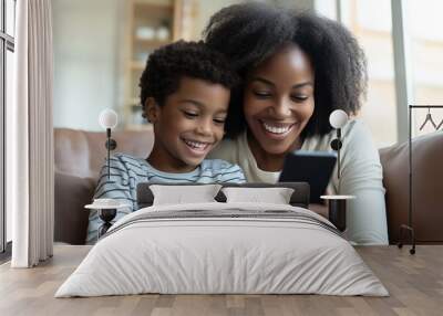 Close-Up of Mother and Son Using Smartphone. African mother and son smiling looking at smartphone, ideal for family and technology themes. Wall mural