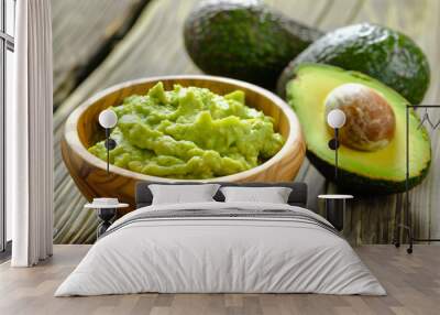 Halved avocado and guacamole in wooden bowl for healthy food concepts. Wall mural