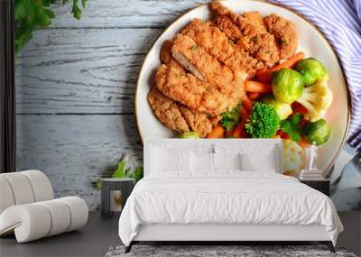 Chicken breast with vegetables. Baked chicken fillet, carrots, Brussels sprouts, broccoli, cauliflower. Food in a plate on a light wooden background. Wall mural