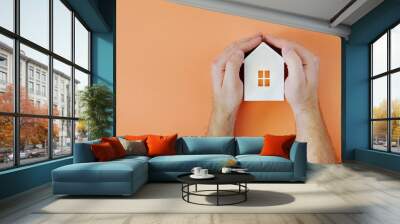 Male hand with model house. Flat lay style Wall mural