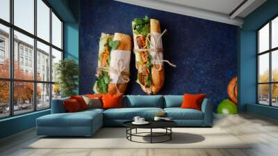 Classical banh-mi sandwich with sliced grilled pork tenderloin, shredded carrots and peeled cucumbers, jalapeno peppers and cilantro on dark blue background with copy space Wall mural