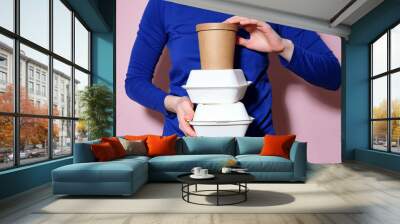 Woman dressed in bright blue shirt holding a pile of takeaway food boxes Wall mural