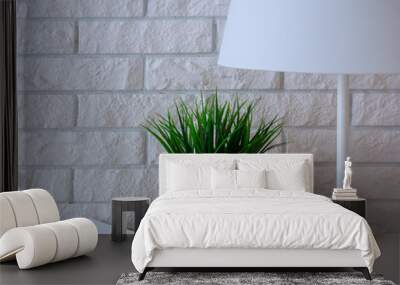 white brick wall with lamp, green potted plant and notebooks on a shelf Wall mural