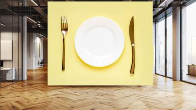 white empty plate and cutlery knife and fork on yellow background Wall mural