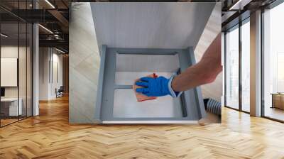 Closeup hand in blue glove with a rag cleaning the kitchen cabinet Wall mural