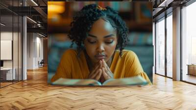 Young Woman in Modern Setting Deep in Prayer with Open Bible Wall mural