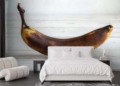 A spoiled darkened banana stands on a white background Wall mural