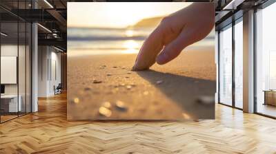 Hand touching sand on beach at sunset Wall mural