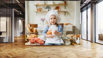 Girl cook 3 years old in a beautiful kitchen, in a chef's hat, in an apron, daylight Wall mural