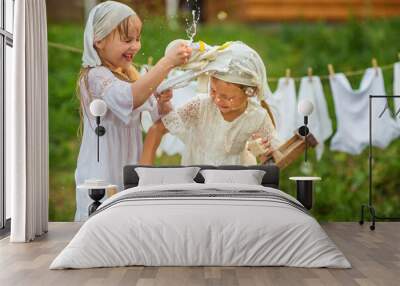 little sisters washing clothes outdoors Wall mural