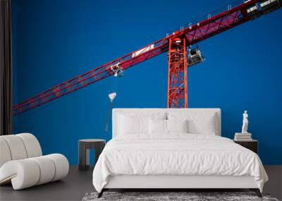 Red construction crane on bright blue sky Wall mural