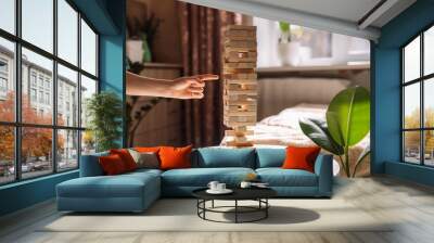 A child slides a wooden block of Jenga game on a white table under sunlight. Wall mural