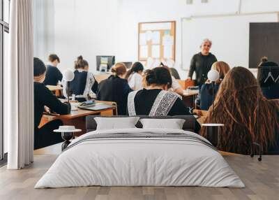 a classroom, a lecture, a lesson is going on, students are listening to the teacher, the teacher talks about the new theme of the lesson Wall mural