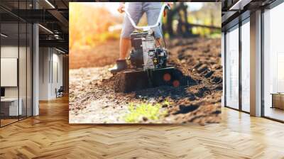 close up photo of young farmer gardener cultivate ground soil rototiller , tiller tractor, cutivator, miiling machine, prepare for planting crop, spring. modern farming, technology agriculture Wall mural