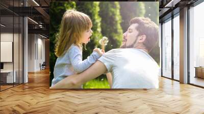 Dad and child blowing dandelion flowers to each other. Wall mural