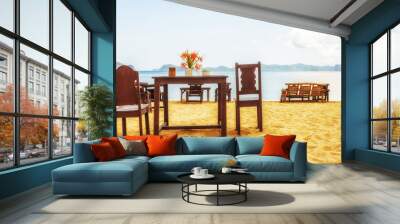 Table and chairs on an exotic beach on a hot sunny day against the blue sea and sky. Wall mural