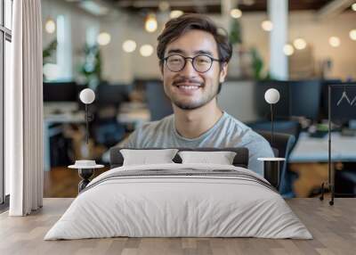 Happy young adult male with glasses smiling in a modern office setting Wall mural