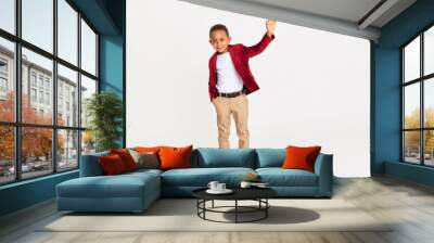 Body language, signs and symbols concept. Full length shot of confident handsome African schoolboy in stylish clothes raising hand, waiving, making greeting gesture, saying Hello, drawing attention Wall mural