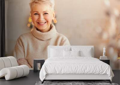 Close up image of fashionable overjoyed European middle aged woman in turtleneck cashmere sweater keeping arms crossed and smiling confidently, waiting family for festive dinner at Christmas Eve Wall mural