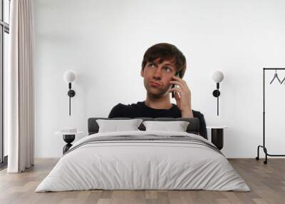 Close up portrait of european man in black t-shirt on neutral white background talking on black mobile and thinking. Guy tell dreams by phone. Communication concept. Wall mural