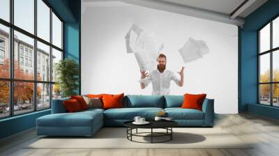 Negative human emotions and reaction. Isolated shot of emotional furious young office worker with beard feeling stressed because of failure at work, throwing papers in air, quitting stressful job Wall mural