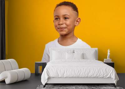 People, childhood, joy and happiness concept. Joyful cheerful Afro American boy of school age having fun, being in good mood, playing after he did his homework, posing isolated at yellow wall Wall mural