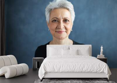 Portrait of beautiful European middle aged female with short gray hair and wrinkles posing isolated wearing black t-shirt having joyful happy facial expression, smiling, being in good mood. Wall mural