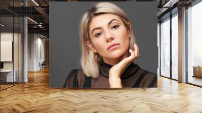 Portrait of beautiful young Caucasian woman with stylish haircut, nose ring and white crystals around one eye keeping hand on her face. Skin care, make up, cosmetics, cosmetology and beauty concept Wall mural