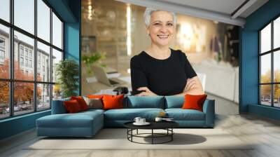 Portrait of joyful confident gray haired mature female freelancer in casual clothes smiling broadly at camera having break while working from home, posing against modern interior background Wall mural