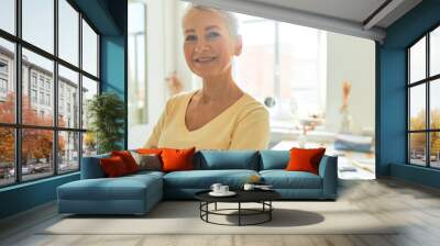 Portrait of successful mature real estate agent with short hairstyle posing in her spacious sunlit office with window in background looking at camera with happy confident smile, crossing arms Wall mural