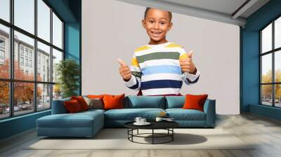 Positive human emotions, reaction and feelings. Emotional happy dark skinned boy in multi colored jumper making thumbs up gesture, expressing agreement, approval, giving his like , smiling broadly Wall mural